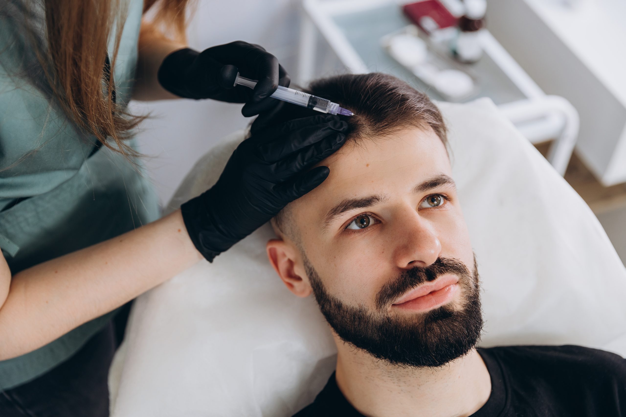 Mesotherapy procedure. A cosmetologist performs a mesotherapy procedure on the head of a young man. Hair strengthening and growth.